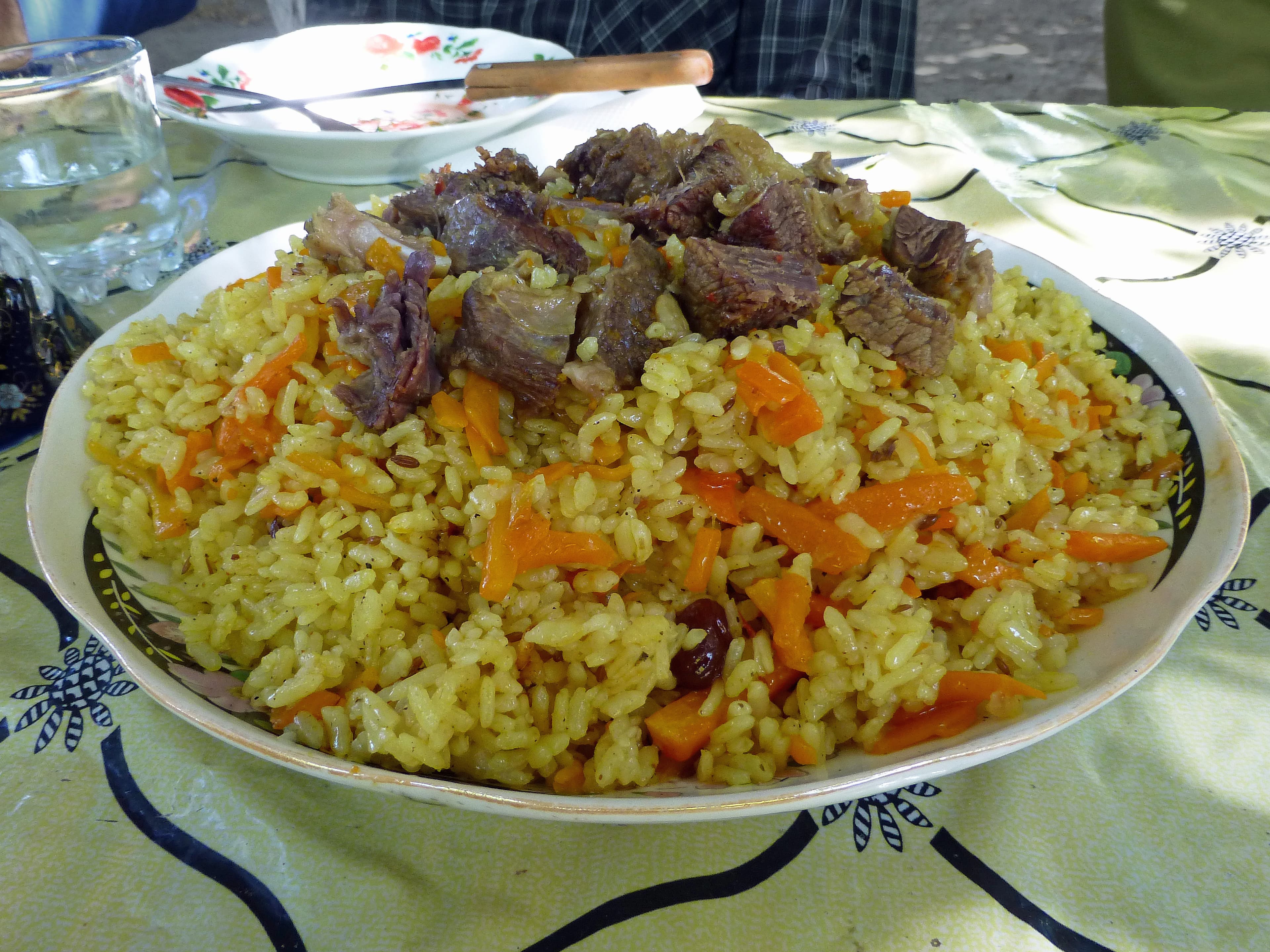 A plate of plov with carrots and meat on top