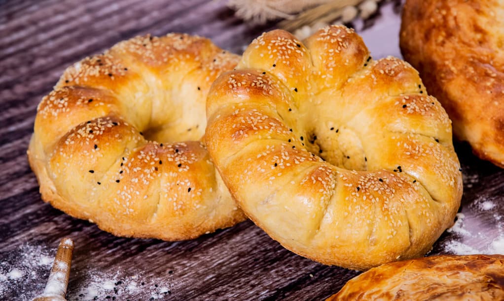 Round tandyr breads with sesame seeds on a dark wooden surface