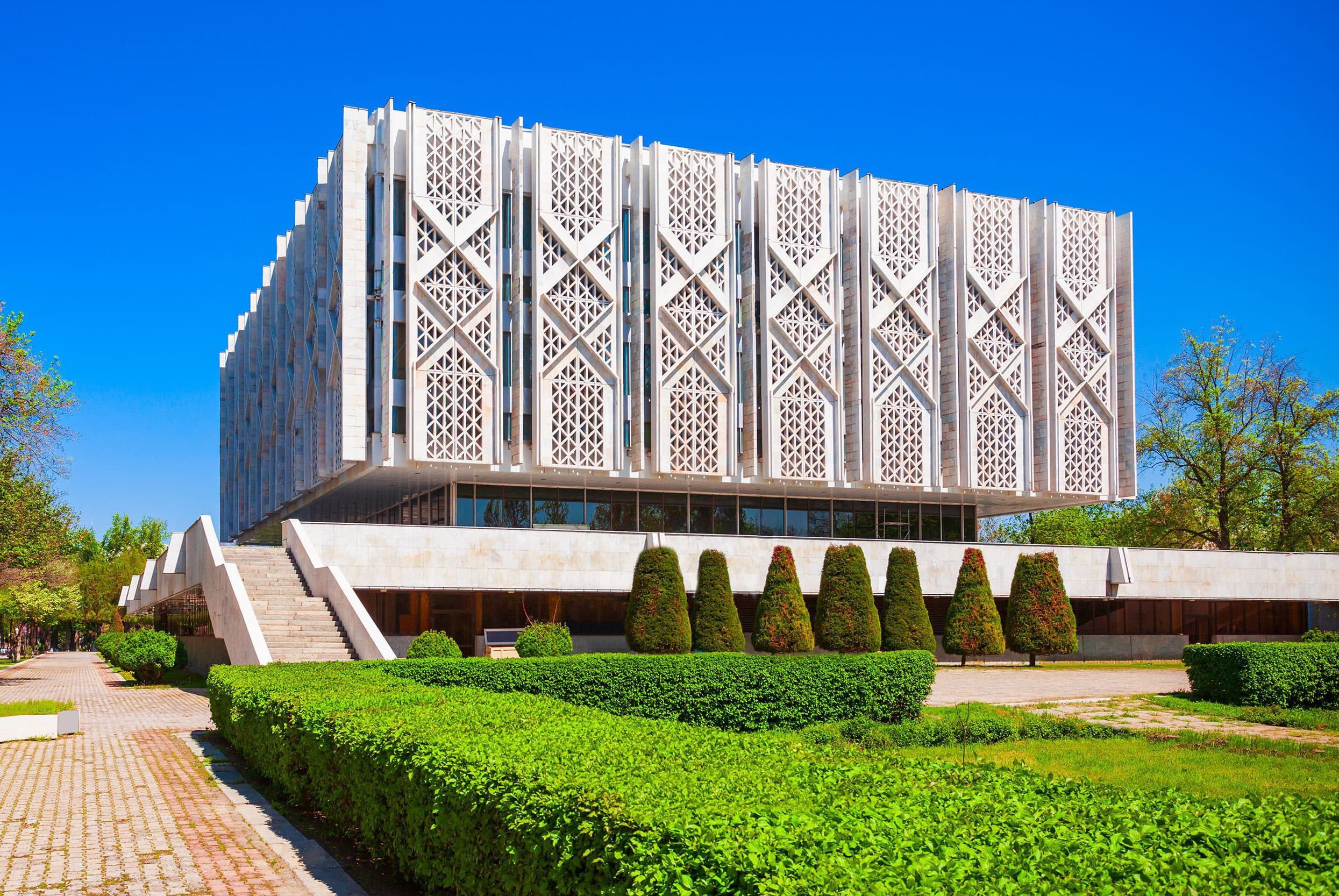 The State Museum of History of Uzbekistan: a white building with a pandjara lattice façade above trimmed hedges