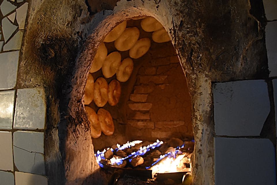 Baker pulling flatbreads from a tandoor