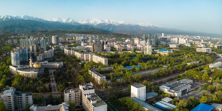 Panorama of Almaty from above: green neighbourhoods, high-rise buildings and mountains on the horizon